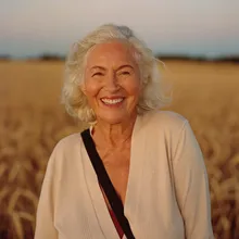 A smiling woman standing in a wheat field at dusk