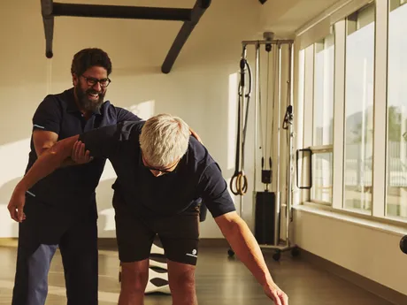 A physical therapist guides a patient through a stretch in the rehabilitation gym